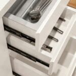 Almacenaje en Cocinas a Medida: 10 Soluciones que Optimizan Cada Centímetro Cajón de cocina extraído mostrando guías metálicas de extracción total y cubertero interior con cubiertos